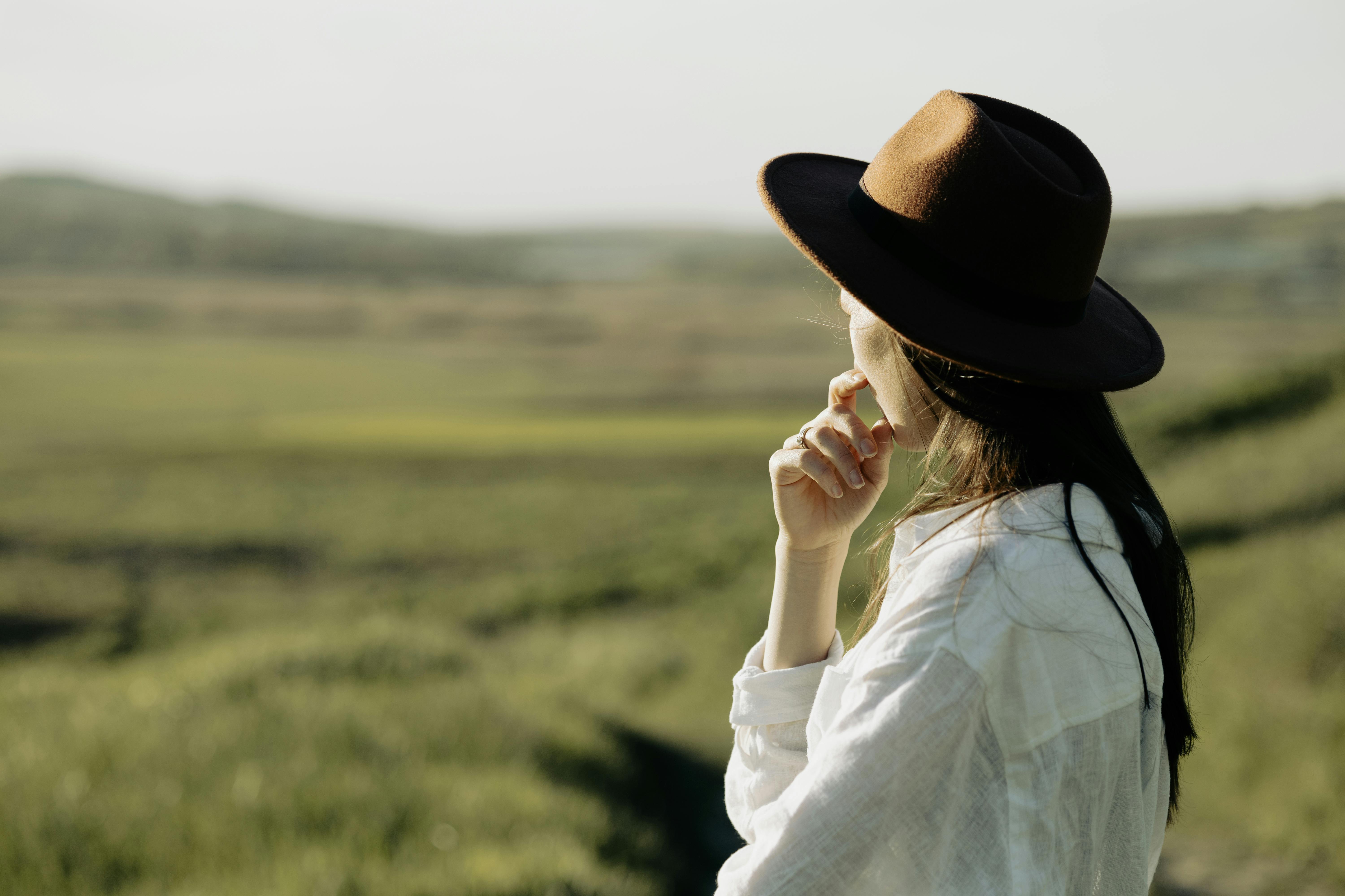 A young lady with a hat on her head looking at the sunset