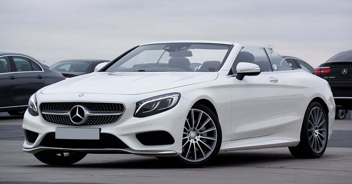Elegant white Mercedes-Benz convertible parked outdoors, showcasing luxury and style.