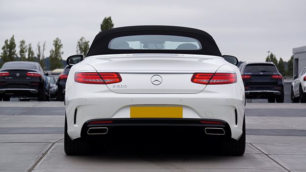 Back view of a sleek, white Mercedes-Benz S500 in an outdoor parking lot, showcasing luxury design.