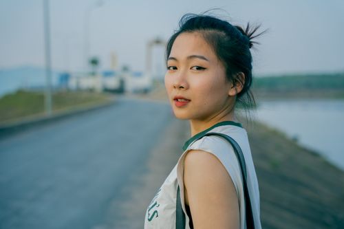 Free Portrait of an Asian woman on a street with an updo, conveying a vibrant summer mood. Stock Photo