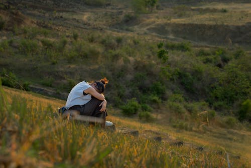 Free Woman Sitting on a Hill at Sunset  Stock Photo