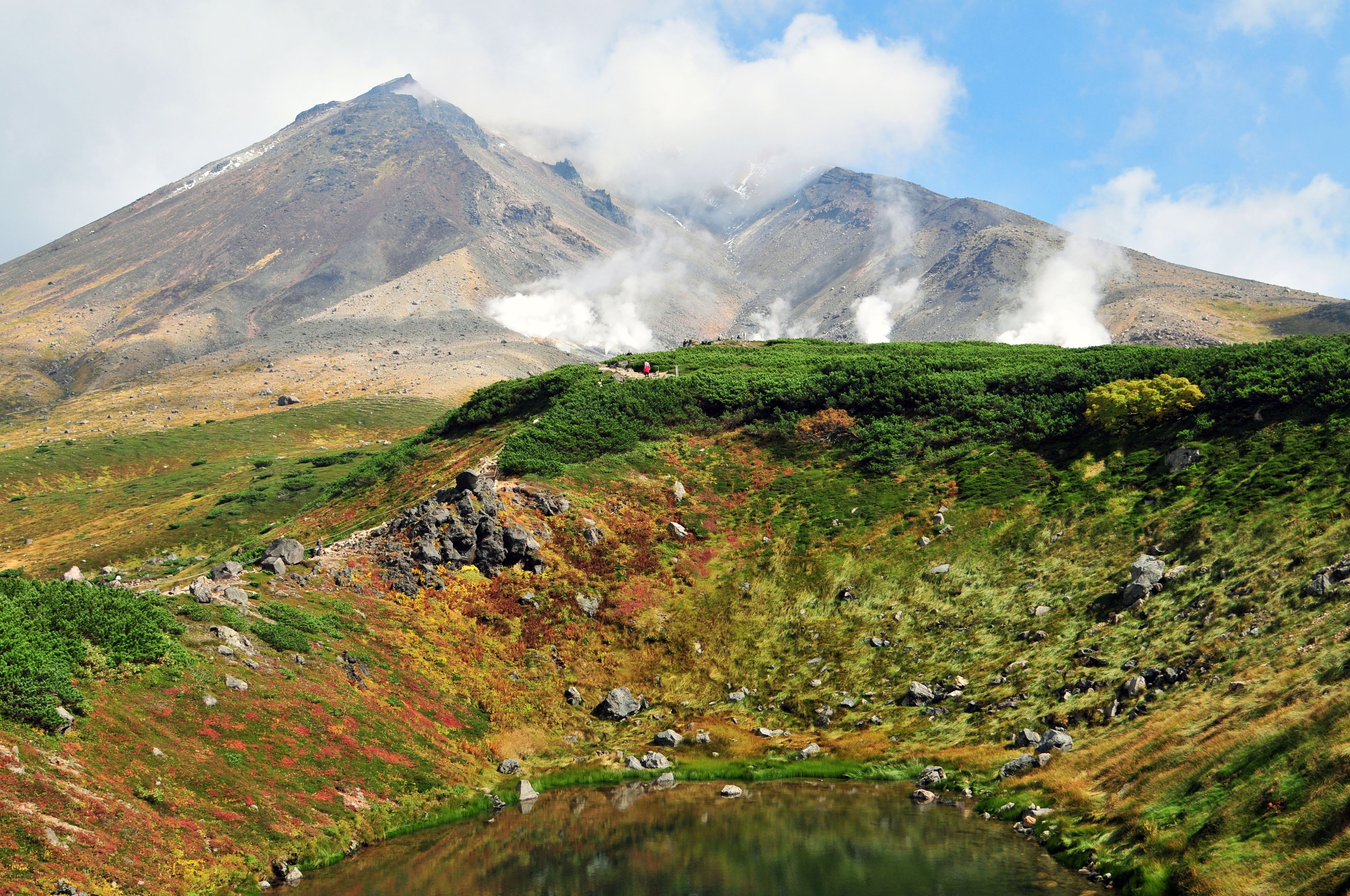 Explore the vibrant autumn landscape of Mount Asahi in Hokkaido, Japan, with colorful foliage and steaming geothermal ve