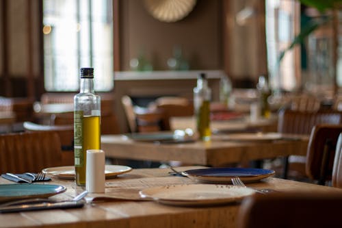 Bottles of Olive Oil and Plates on Each Table in a Restaurant 