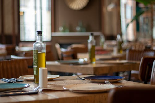 Free Bottles of Olive Oil and Plates on Each Table in a Restaurant  Stock Photo