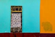 Colorful facade with ornate metal bars on a window in Trinidad, Cuba. Bright blue and orange walls.