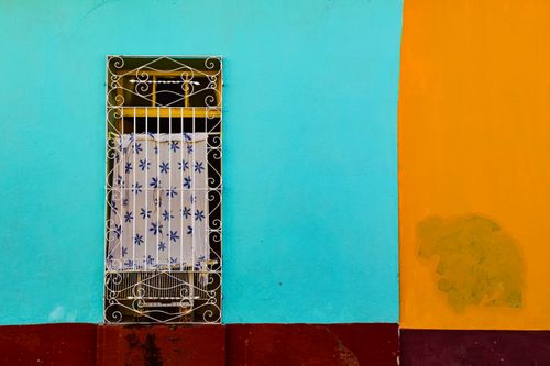 Free Colorful facade with ornate metal bars on a window in Trinidad, Cuba. Bright blue and orange walls. Stock Photo