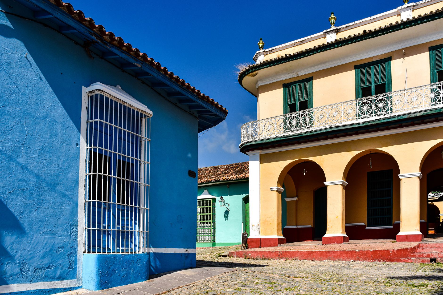 Vibrant colonial buildings under a clear blue sky in Trinidad, Cuba.