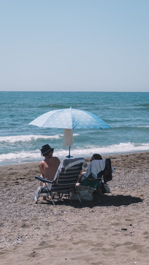 Tourists Sitting under and Umbrella on the Beach 