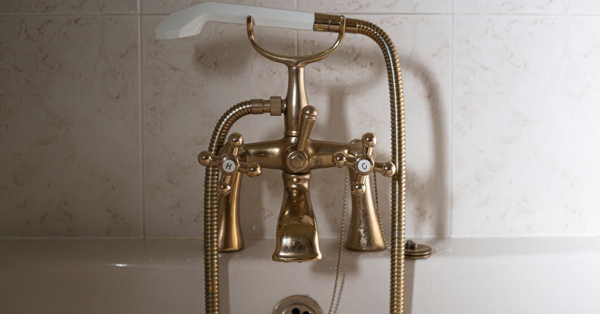 Close-up of a classic brass bathtub faucet with a ceramic hand shower in Greystoke, England.