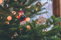 特写镜头里，一棵装饰好的圣诞树上挂着雪人装饰品，灯光闪闪发亮