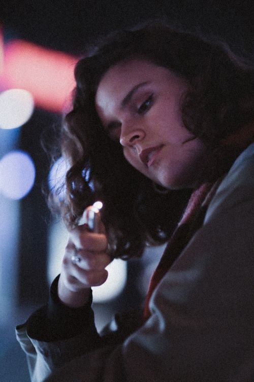 Free Portrait of a young woman with a lighter in a night setting. Stock Photo
