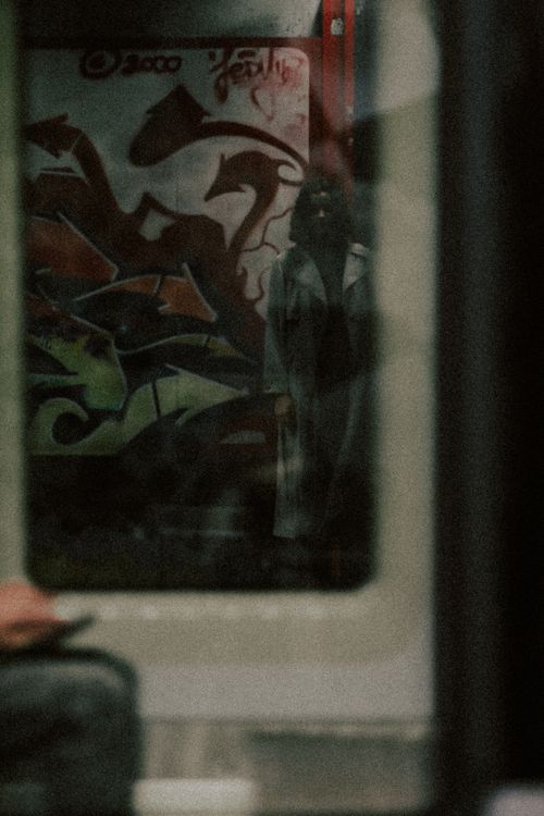 Free A shadowy figure in a subway with vibrant graffiti art, captured through reflection. Stock Photo