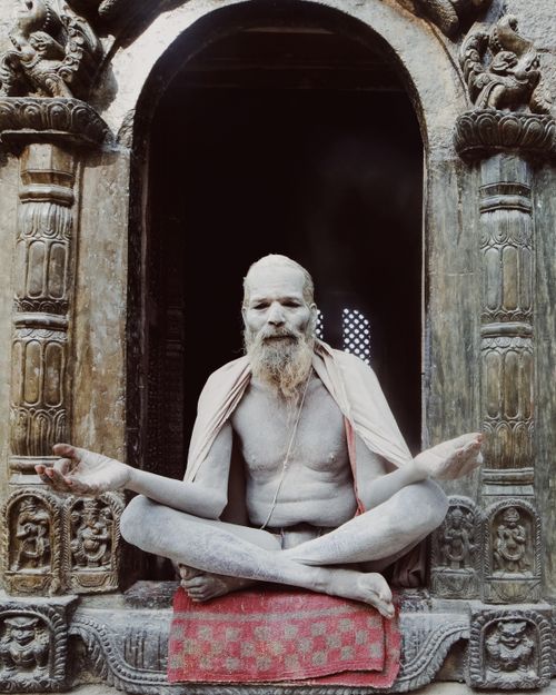 Free An ascetic sage meditates cross-legged in a historic stone temple, embodying serenity. Stock Photo