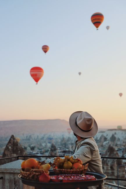 A person enjoying sunrise with hot air balloons over Cappadocia, Turkey.