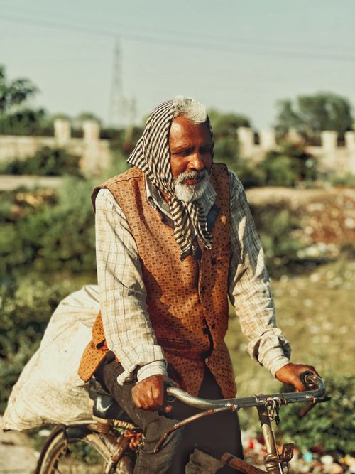 Free Senior man with headscarf cycling outdoors on a sunny day, embracing lifestyle and culture. Stock Photo