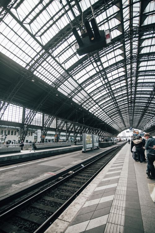 Free A bustling urban train station with commuters waiting on the platform under a glass roof. Stock Photo