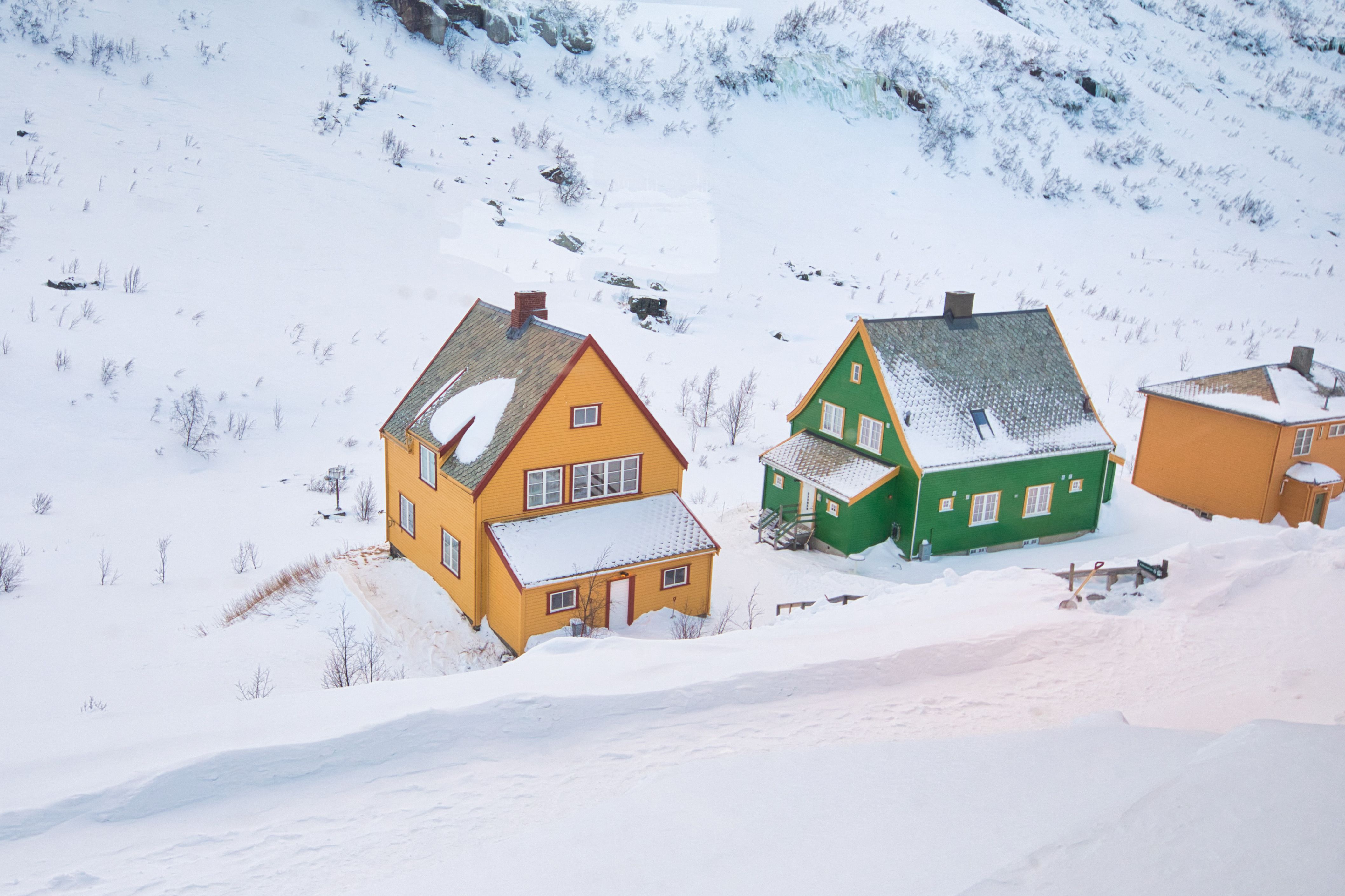 Brightly painted houses amidst snowy mountains in Gudvangen, Vestland, Norway.
