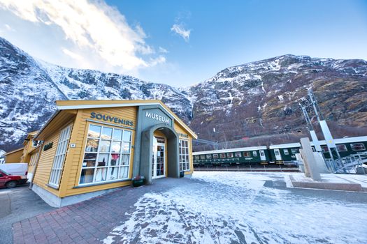 Snowy landscape with a museum and train by mountains in winter, offering scenic views.