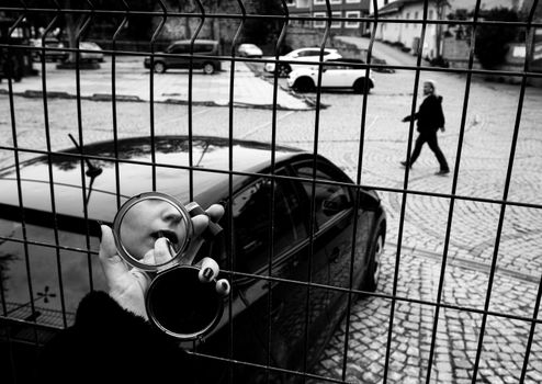 A unique black and white capture of a woman applying lipstick through a fence in Istanbul.