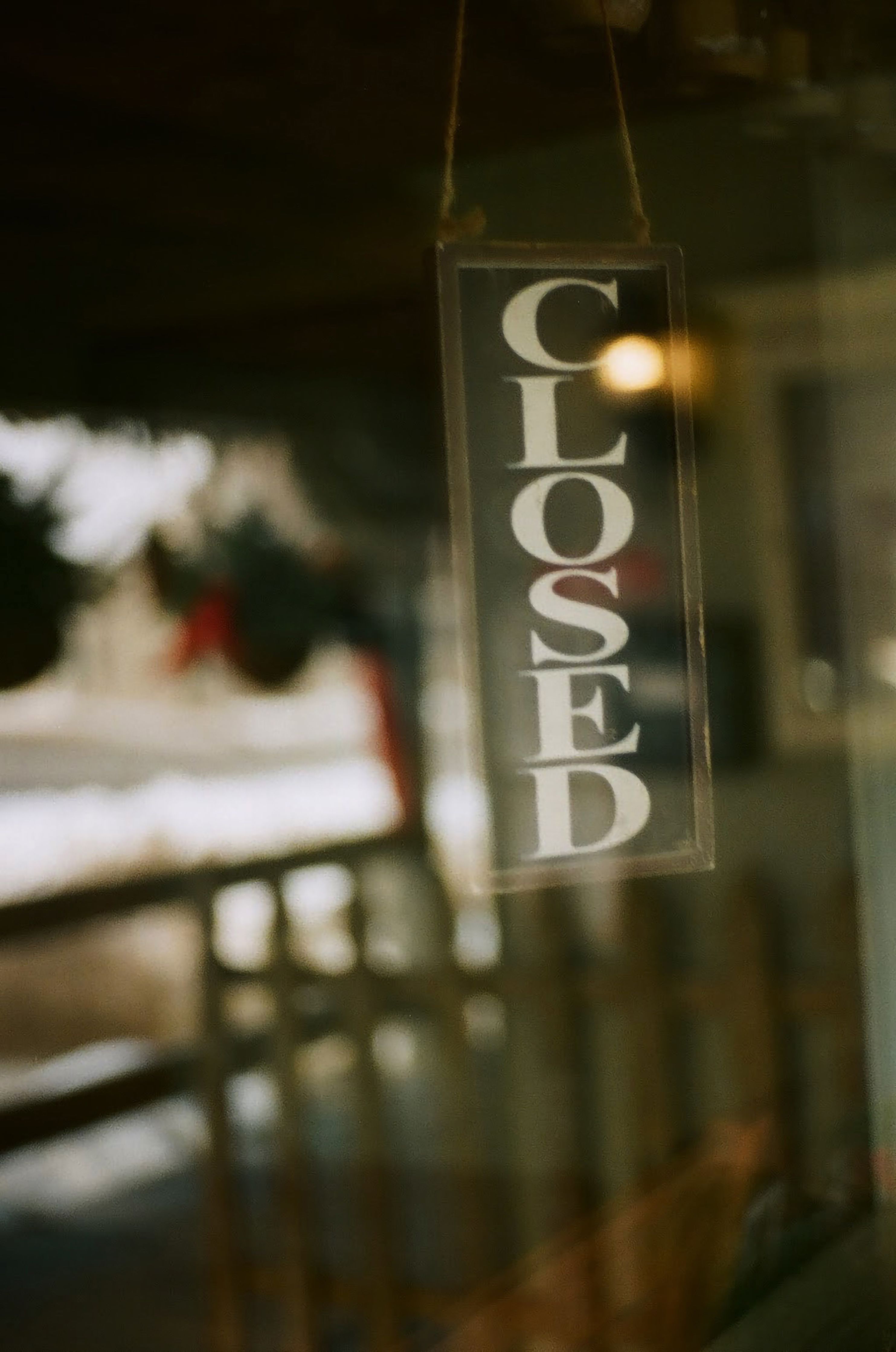 Vertical shot of a closed sign hanging in a store window with reflections.