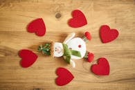 木头上铺着一个欢快的雪人，雪人身上还装饰着红色的毛毡心，非常适合营造舒适的冬季氛围