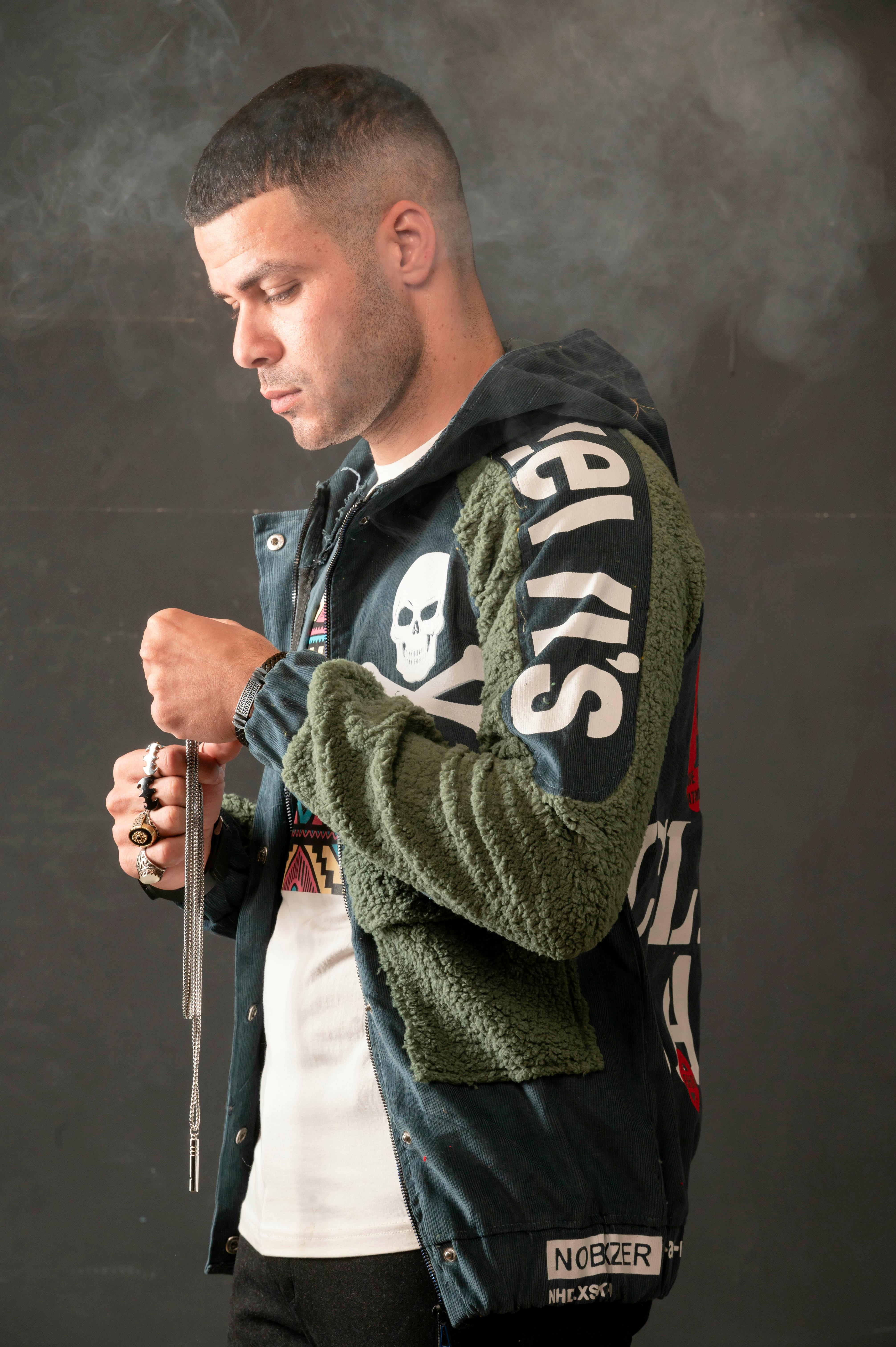 Portrait of a stylish man in a graphic hoodie holding a necklace, showcasing street style fashion.