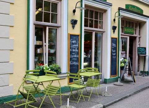 A picturesque Austrian café with green outdoor seating on a vibrant city street.