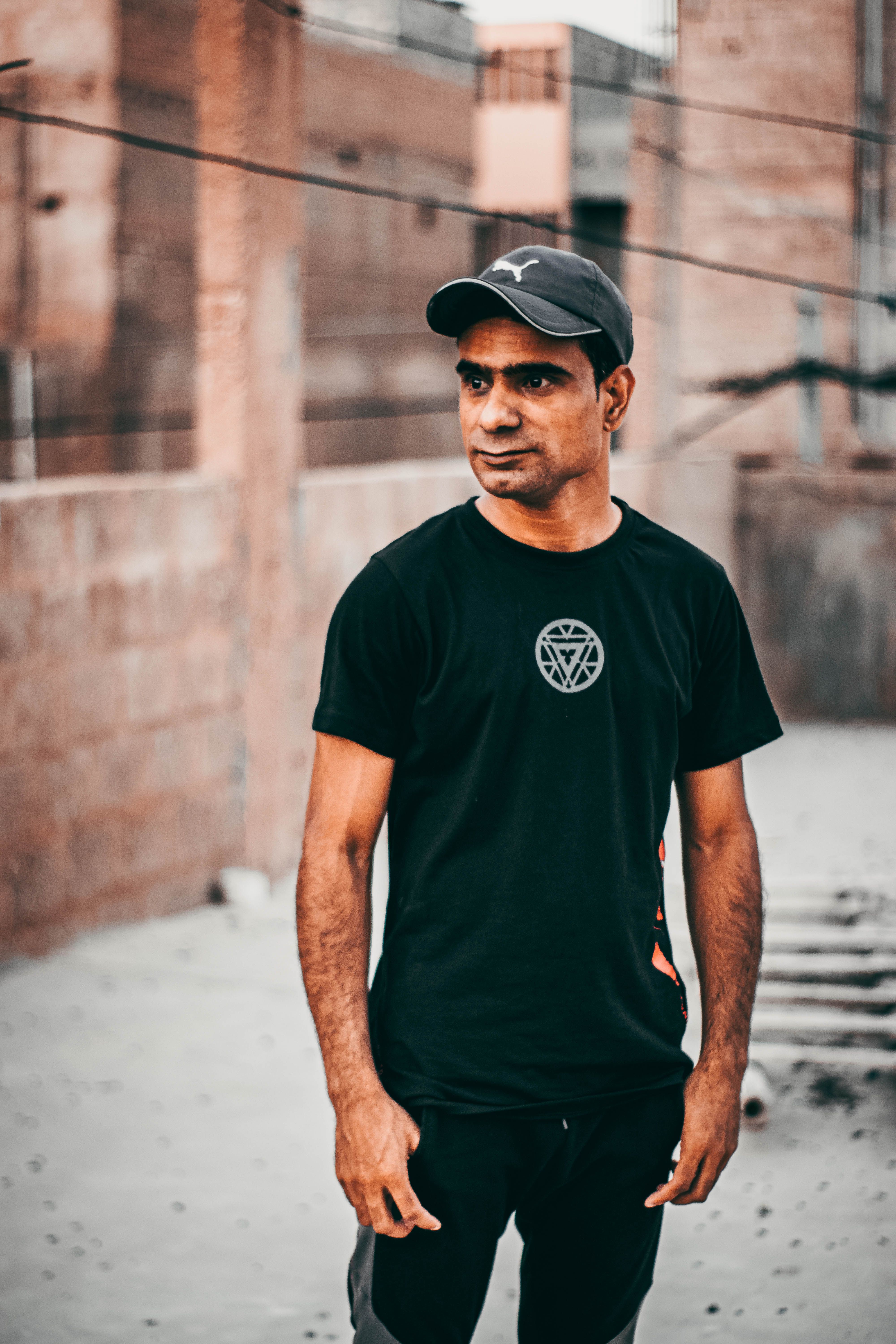Mid adult man standing outdoors in casual street style attire on an urban rooftop.