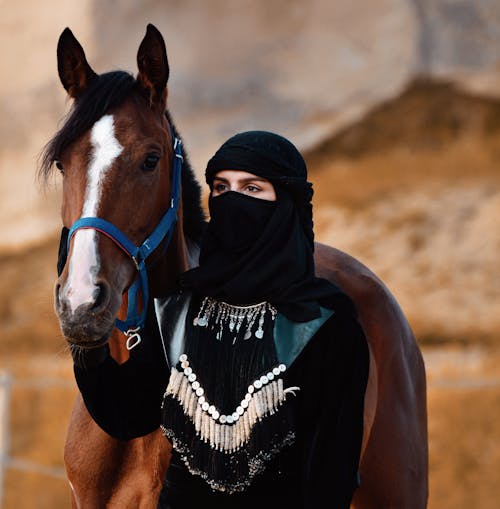 Photo of a Woman with a Covered Face and a Horse 