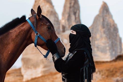 Photo of a Horse and Woman in a Black Headscarf 