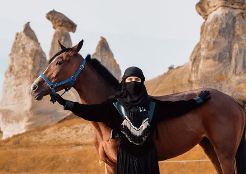 Free Middle Eastern woman with horse in scenic Cappadocia, Turkey. Explore culture and nature. Stock Photo