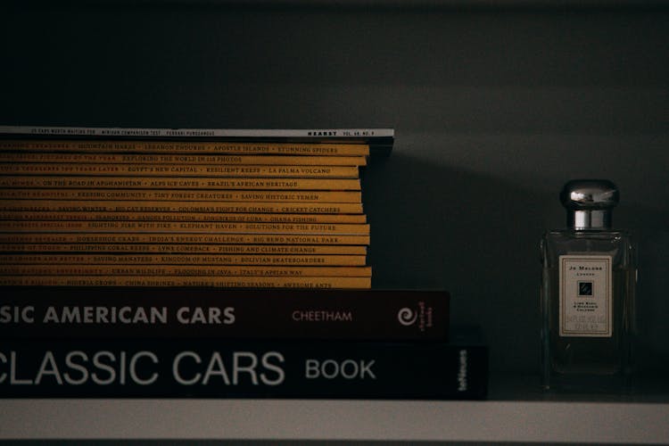 Stack Of Books And A Perfume Bottle Standing On A Shelf