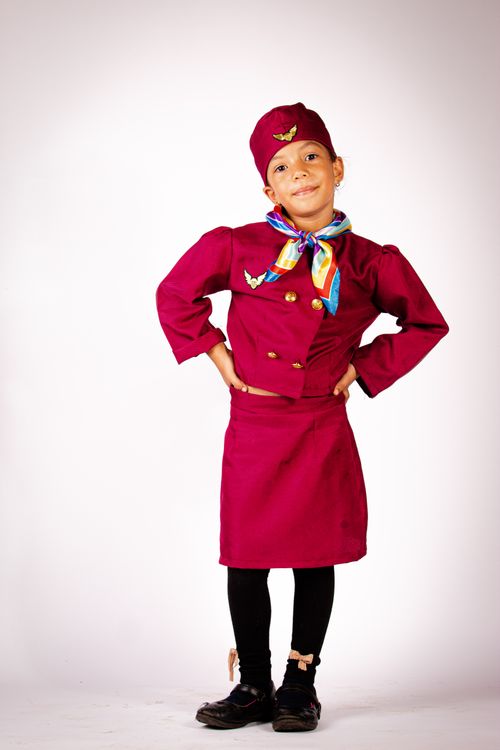 Free Young child posing in vibrant airline attendant costume against a white backdrop. Stock Photo