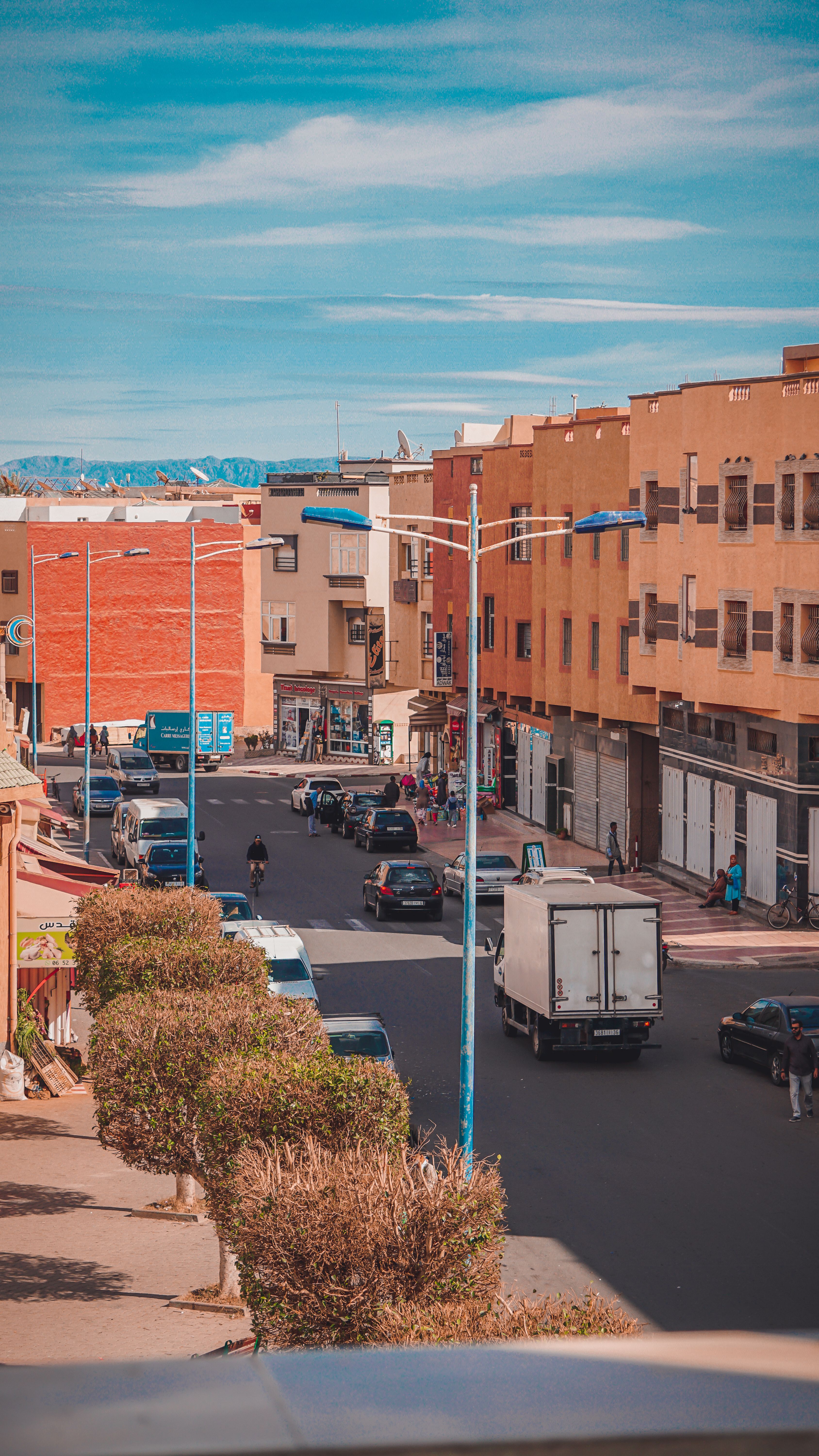 A vibrant urban street scene featuring modern residential buildings and light traffic under a blue sky.
