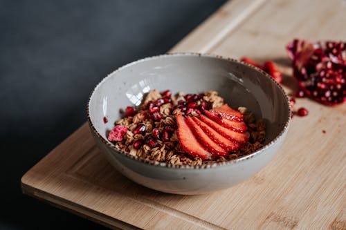 Gray Bowl of Cereals and Sliced Strawberries on a Wooden Cutting Board