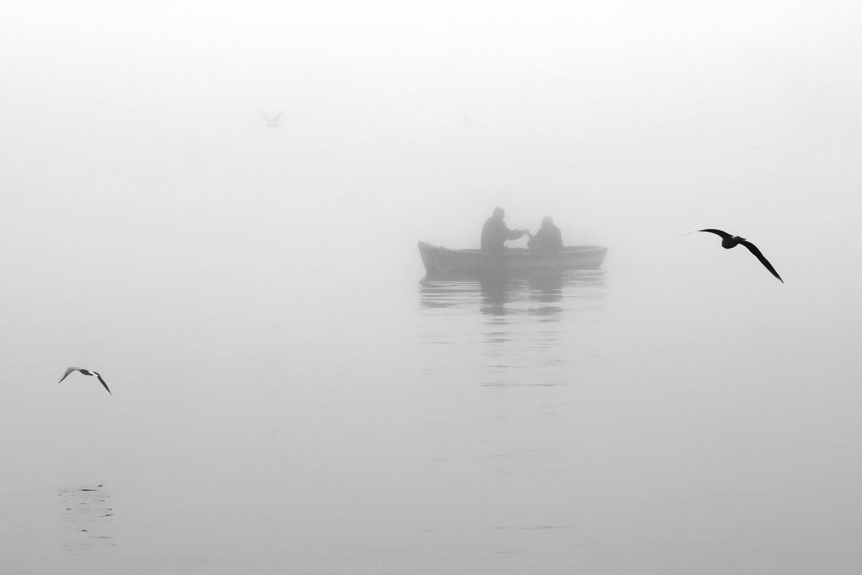 Silhouetted boat on a foggy lake creating a mysterious ambiance.