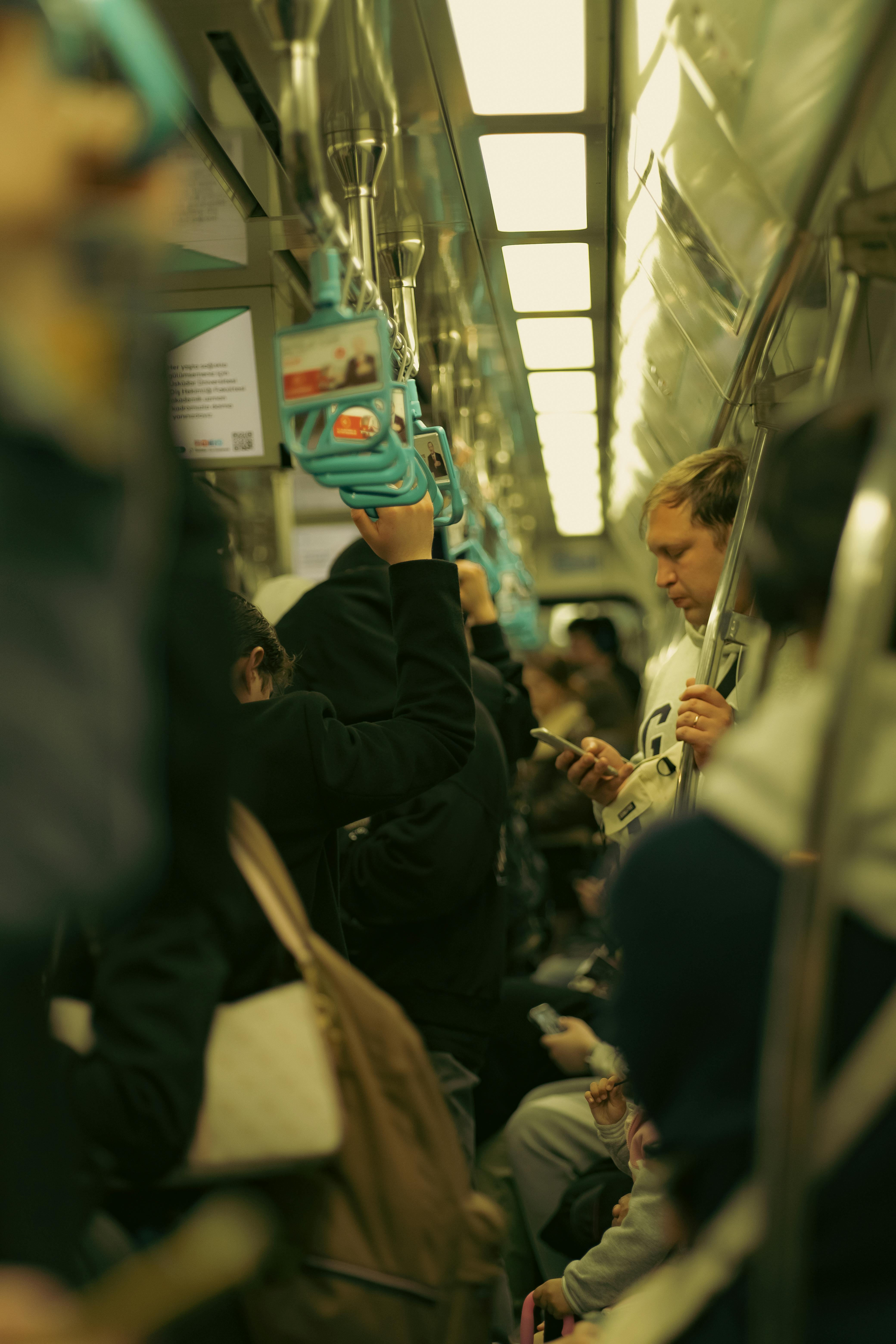 A crowded subway train with commuters standing and using phones, showcasing urban life.
