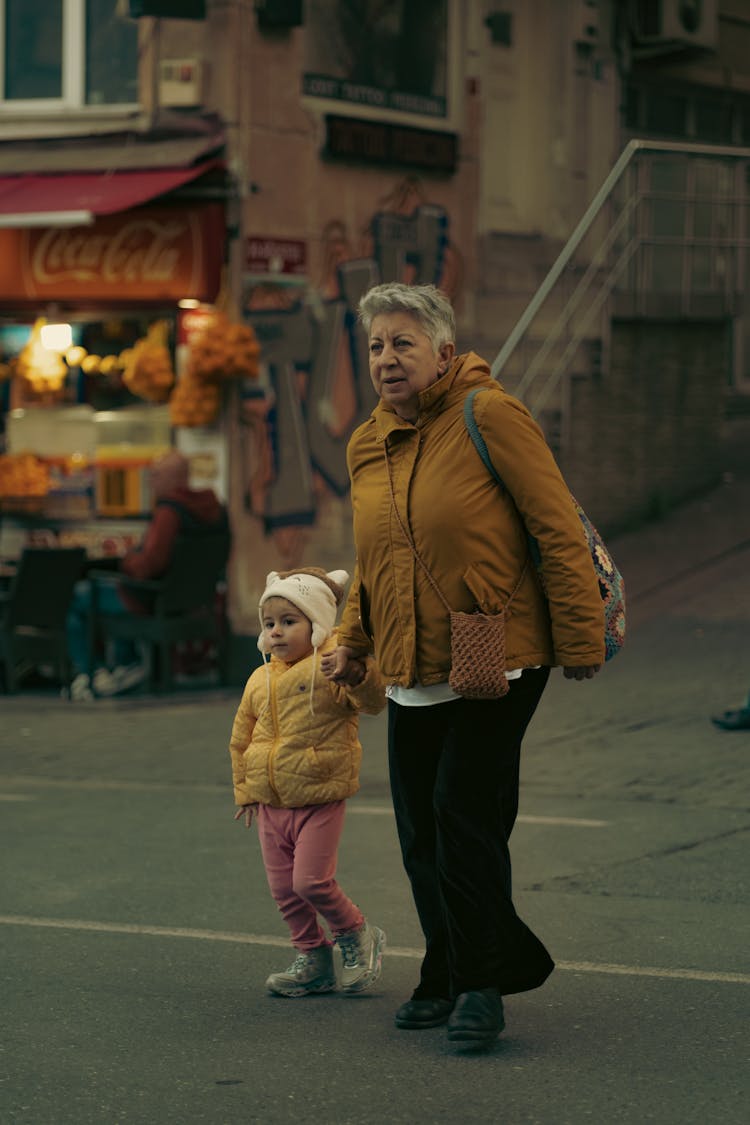 Candid Picture Of Grandmother With Her Granddaughter Walking On The Street In City 