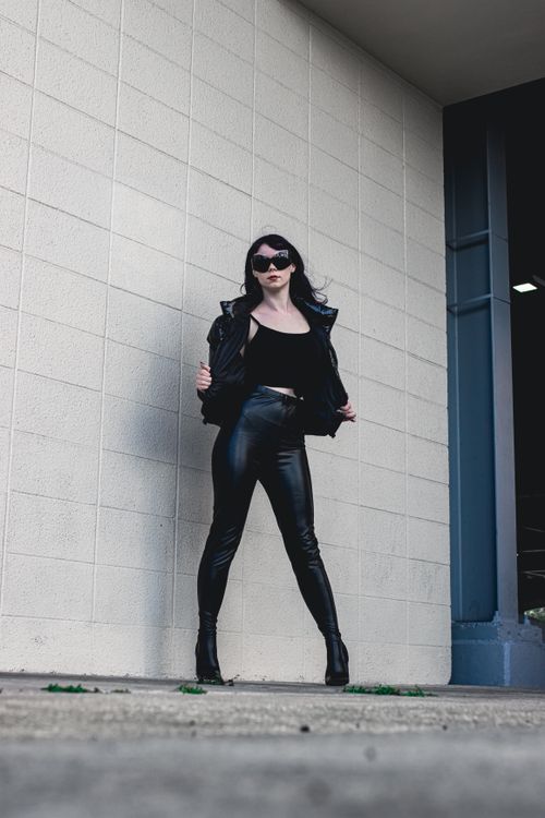 Free Stylish woman in black leather standing confidently against a white wall. Stock Photo
