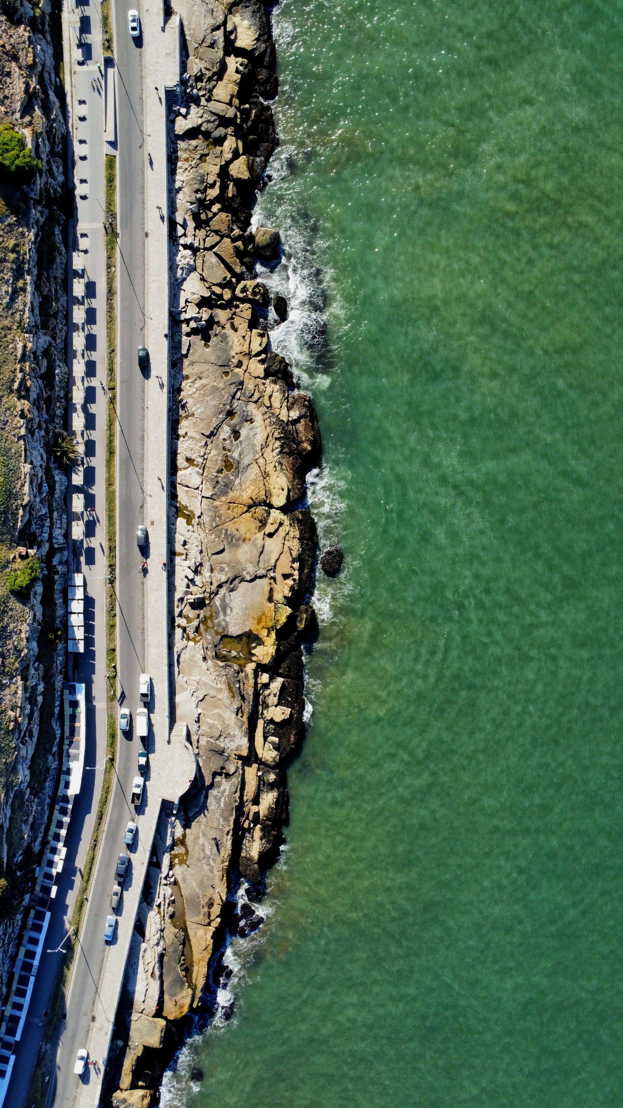 A stunning aerial view of a coastal road alongside rocky cliffs meeting the ocean in Argentina.