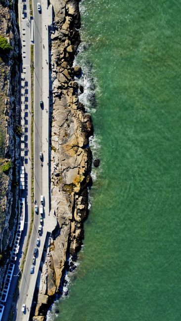 A stunning aerial view of a coastal road alongside rocky cliffs meeting the ocean in Argentina.