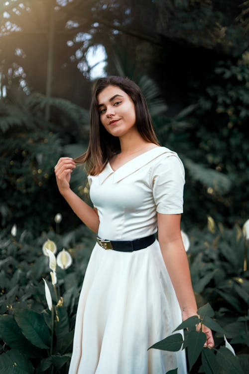 Young Woman in a White Dress Posing in a Garden 