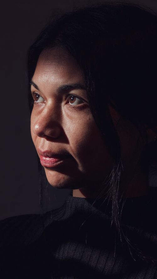 Free Close-up profile of woman in a turtleneck, illuminated by dramatic lighting. Stock Photo