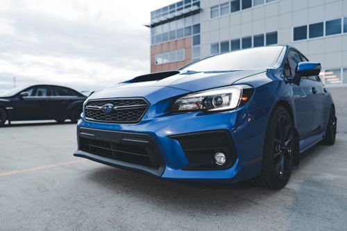 Free A blue Subaru WRX sports car parked in an urban parking lot on a cloudy day. Stock Photo