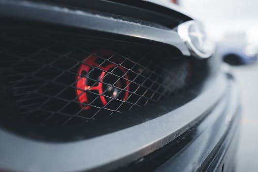 Detailed view of a sports car grille featuring a red accent, emphasizing style and modern design.