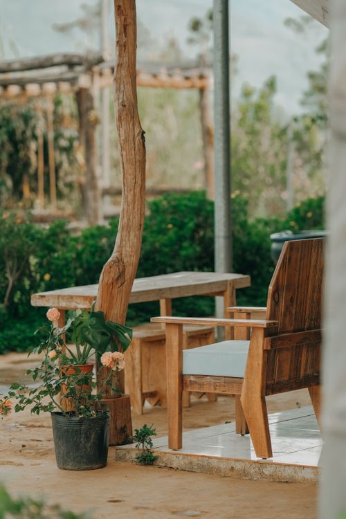 Free Cozy wooden bench and table on a tranquil veranda surrounded by lush greenery. Stock Photo