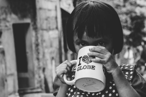 Grayscale Photography of Girl Drinking Water on Mug