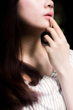 Close-up portrait featuring a woman's lips and hand pose with elegant expression and dramatic lighting.