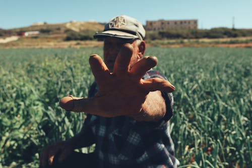 Elderly Man Standing in a Field and Reaching His Hand Toward the Camera 