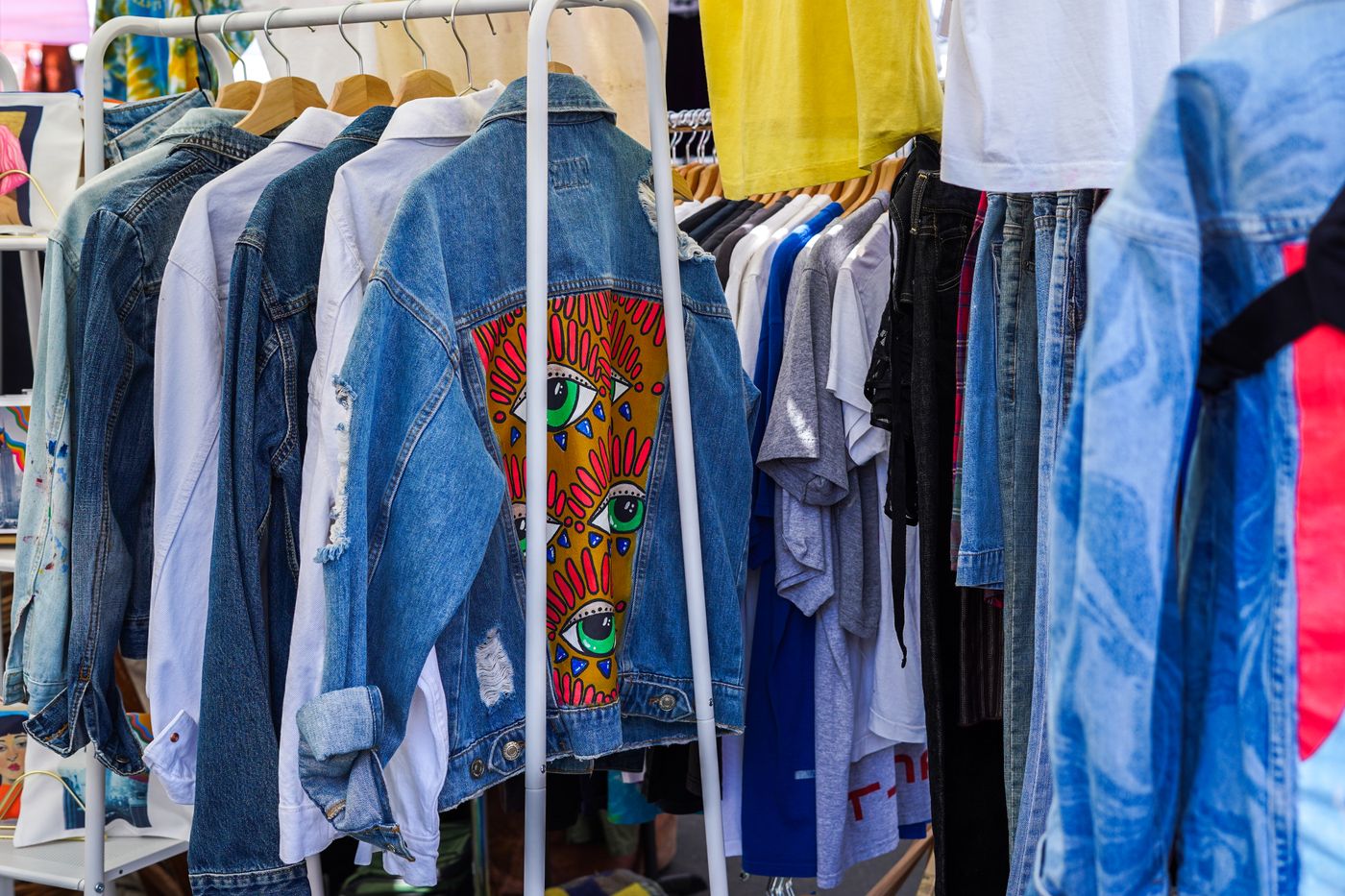 Colourful vintage denim jackets and shirts arranged on a market clothing rail